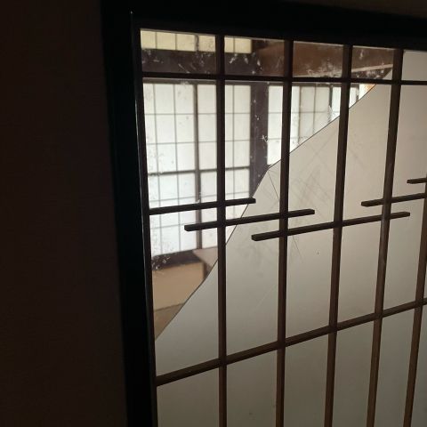 A sliding door with a wooden lattice over frosted glass. A large triangular piece of the glass is missing, showing the room beyond.