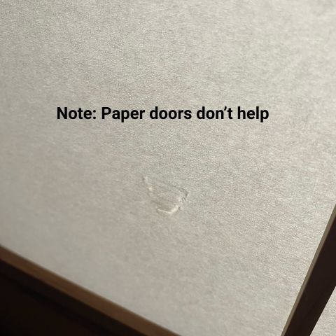 A dent pressed into a paper sliding door, with overlaid text that reads: Note: Paper doors don't help.
