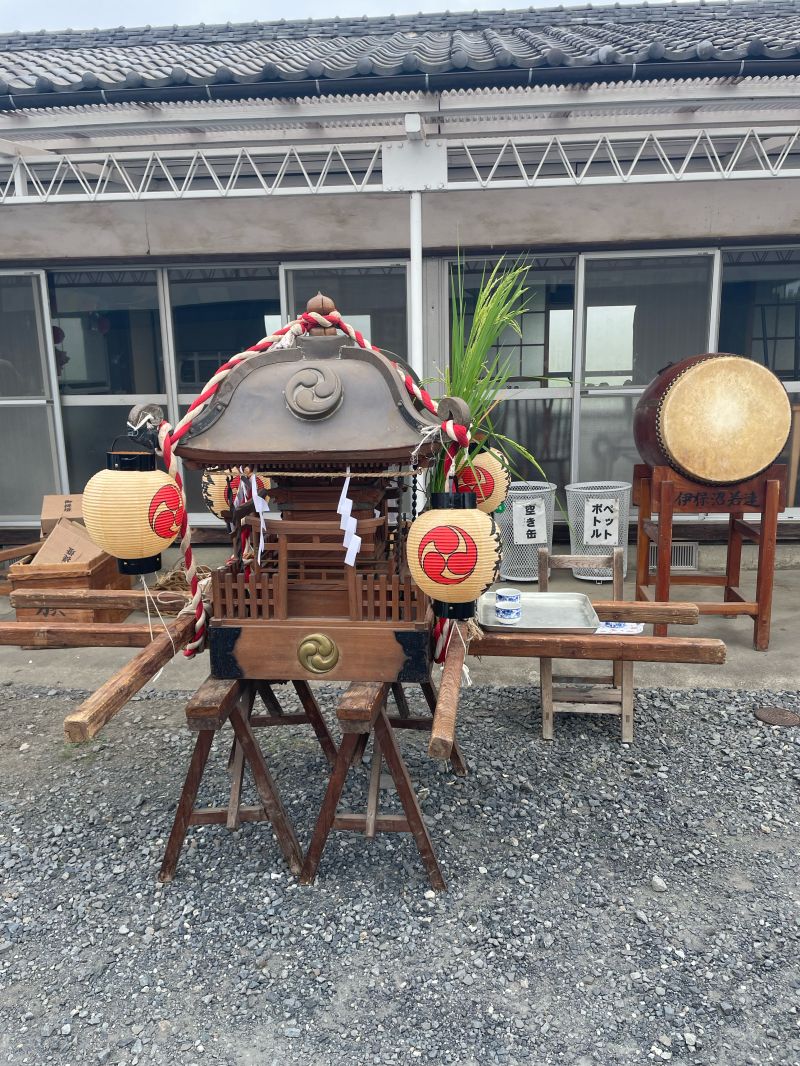 The neighborhood mikoshi resting on sawhorses outside the community center, with lanterns, rope, and a taiko drum beside it