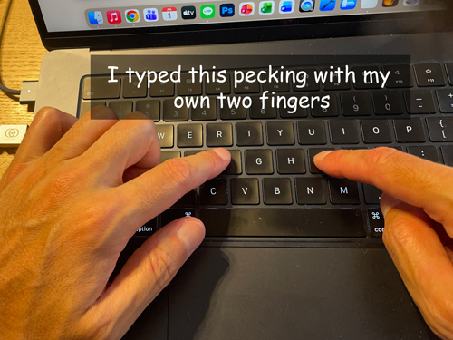 A hand pecking at a laptop keyboard with two fingers, overlaid with the caption: 'I typed this pecking with my own two fingers.'